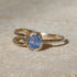 Gold ring with a blue gemstone on a beige surface