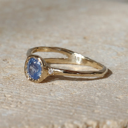 Gold ring with a blue gemstone on a beige surface