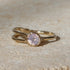 Gold ring with a pink gemstone on a beige surface