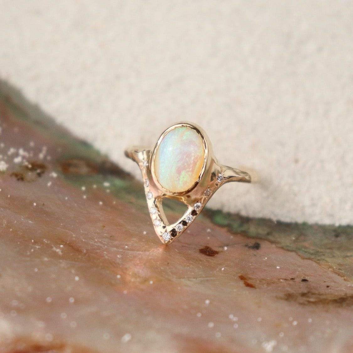 Elegant opal ring featuring a V-shaped design adorned with sparkling diamond accents.