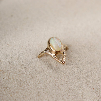A partial side view of an elegant opal ring featuring a V-shaped design adorned with sparkling diamond accents