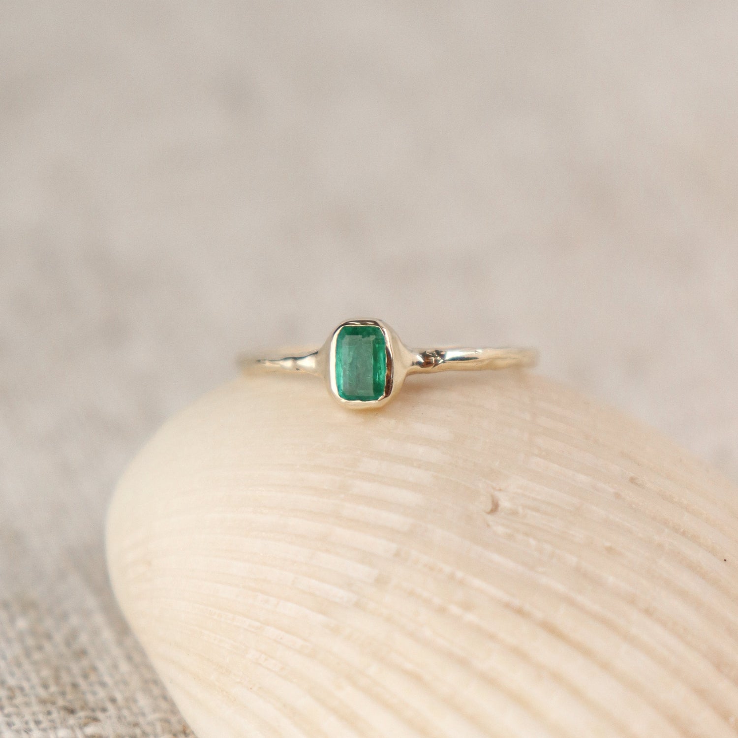 Mini emerald ring with a vibrant green gemstone bezel set in delicate gold band.