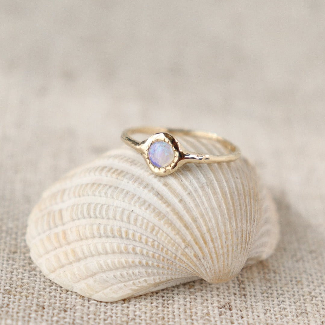 Unique round opal ring, set on a slender band with small tick-like accents that radiate like a starburst, creating a mesmerizing and celestial jewelry piece.