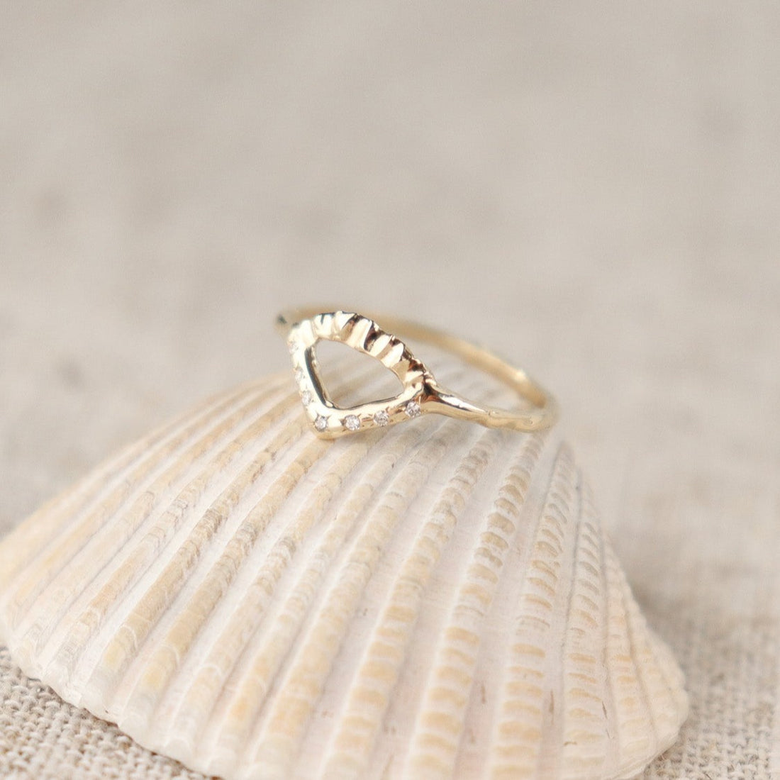 Elegant gold ring with V-shaped diamond detail and arched fin texture.