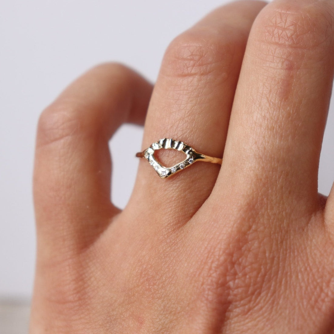 Elegant gold ring with V-shaped diamond detail and arched fin texture, worn to show scale.