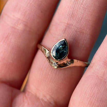 Gold ring with a blue gemstone on a person&