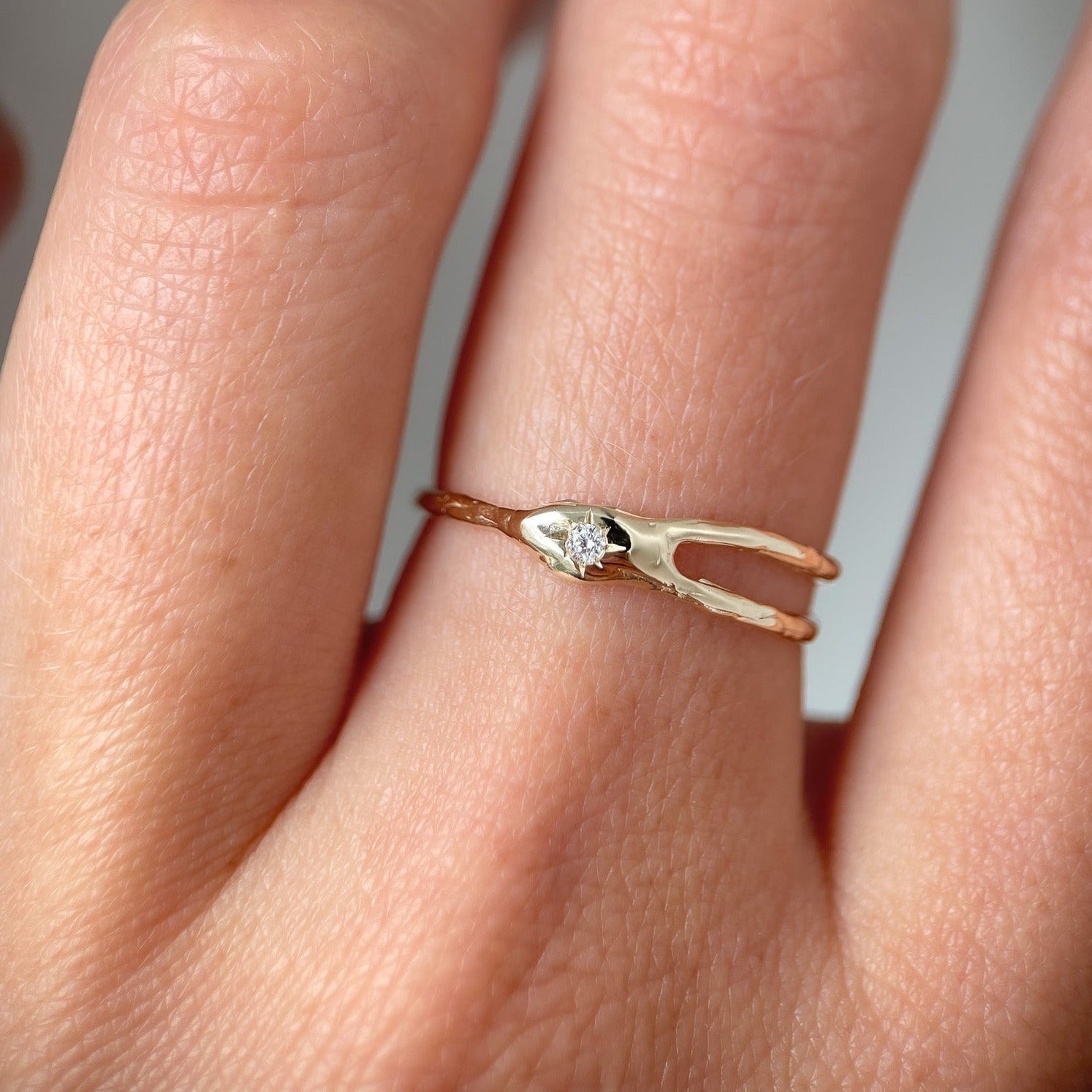 Asymmetrical gold ring with split band centered around a star-set diamond, resembling a shooting star for a unique and celestial design.
