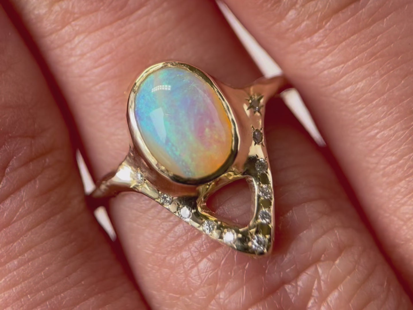 A close up  video of an elegant opal ring featuring a V-shaped design adorned with sparkling diamond accents