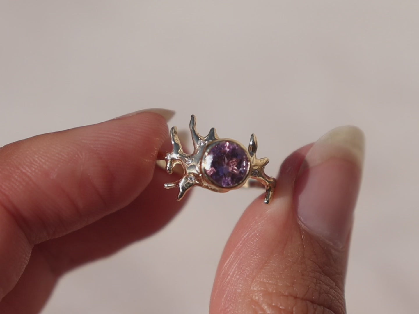 close up video of an exquisite round brilliant cut ametrine gemstone, bezel-set in a gold band with an organic coral-like design, adorned with sparkling diamond accents