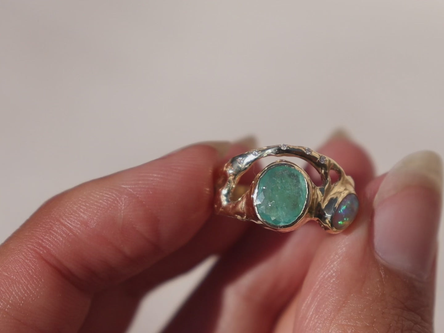 A video  of an organically shaped ring with a stunning Paraiba tourmaline and opal, bezel-set and accented with dazzling diamonds.