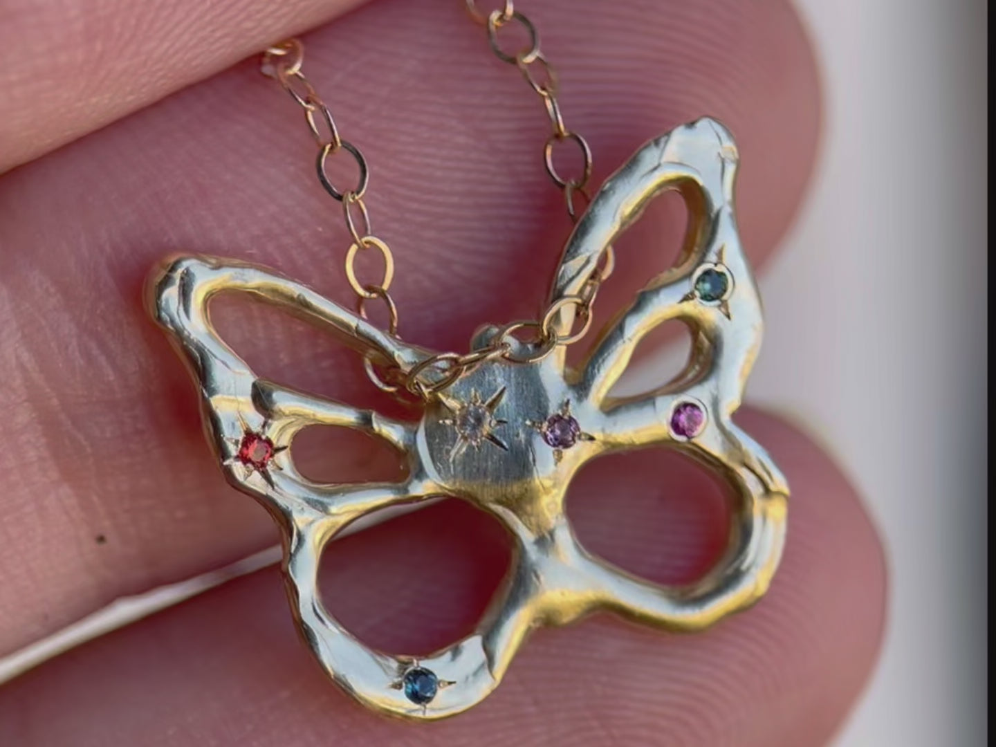 Close up video of  a multi colored gemstone studded butterfly charm.