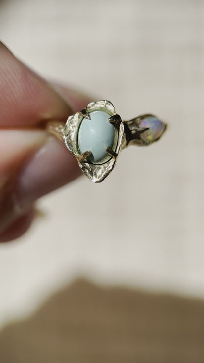 a close up video of a gold flower ring with variscite and opal