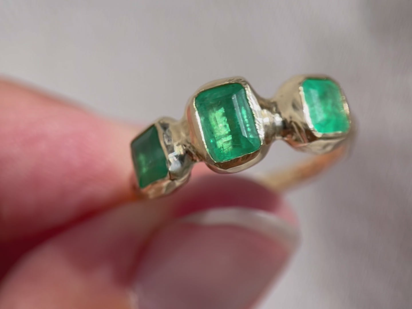 up close detail video of a trio emerald ring bezel set in 14k gold