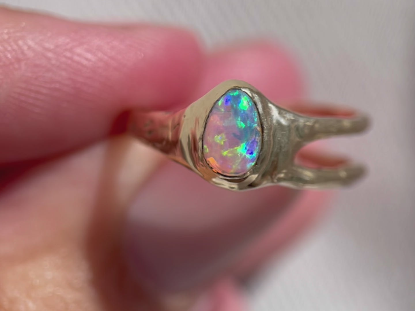a video of a small pear shaped opal set in 14k gold with an asymmetric band design