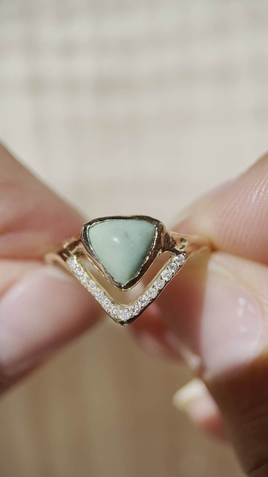 close up video of a trillion variscite bezel set in gold with a v-shaped row of pave diamonds