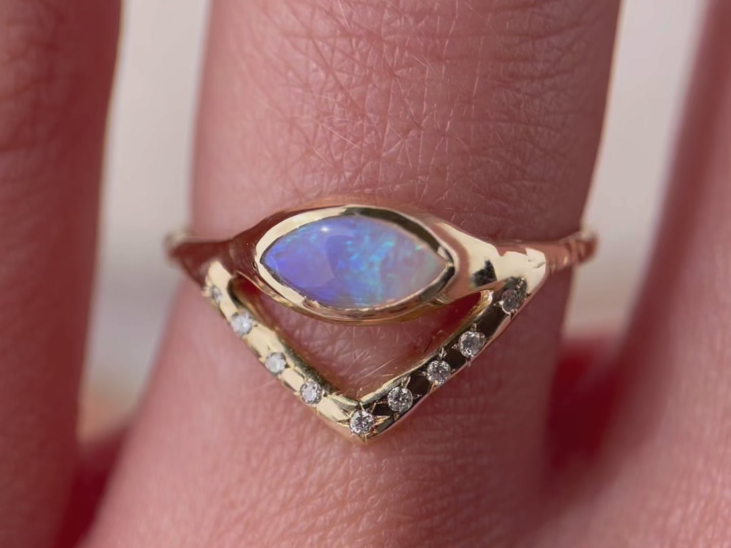 A close up video of a horizontal marquise opal on a slender band with an organic diamond-set V accent, creating a stunning and unique ring design.