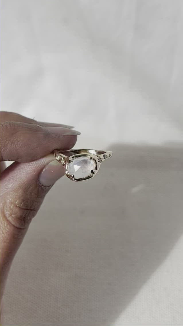 video of a close up of a gold moonstone ring with diamonds on the sides of the band