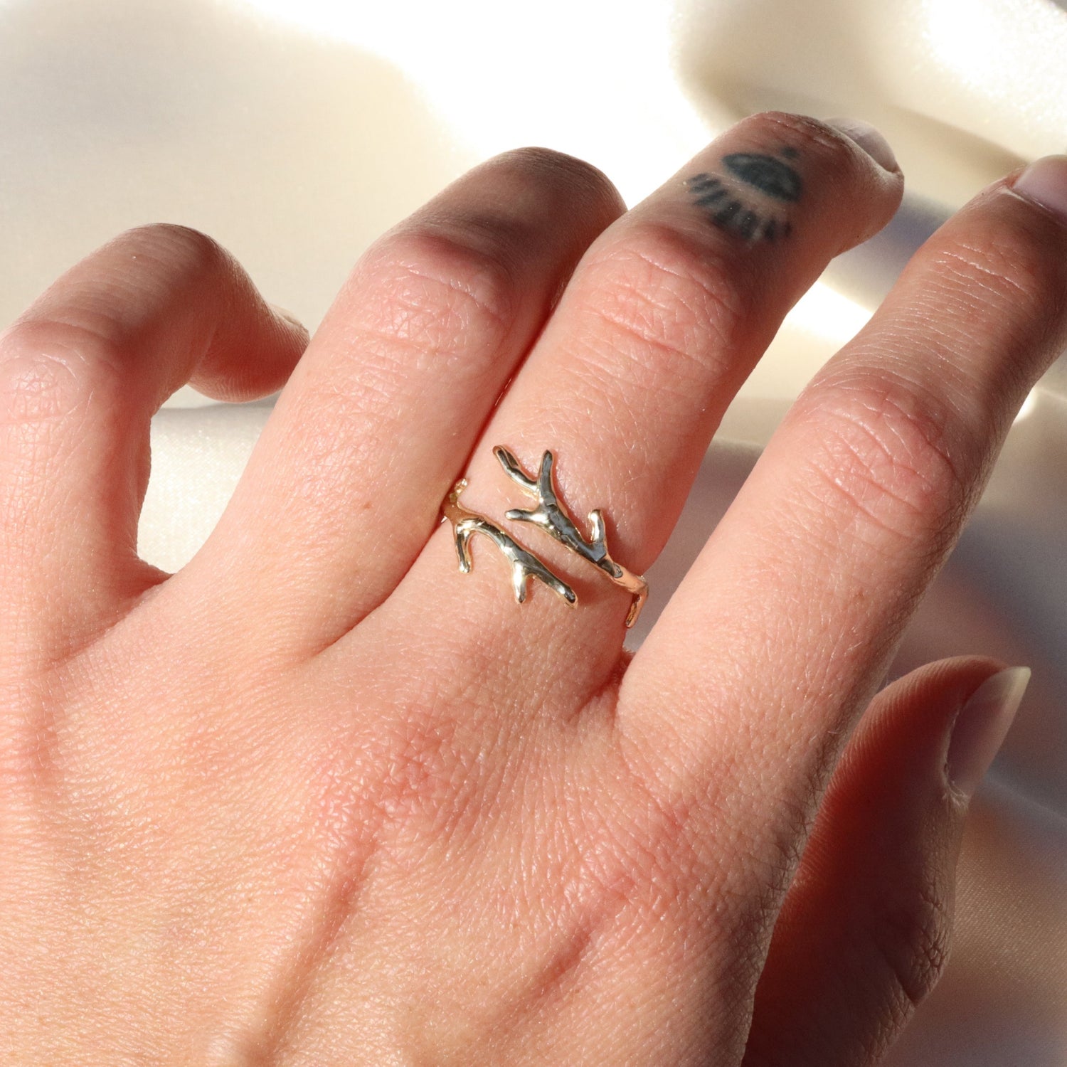 A gold coral branch ring is shown on a finger. This ring is open, showing that it is adjustable.