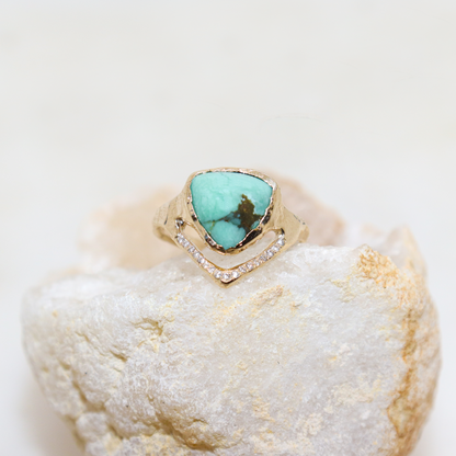 A trillion variscite is bezel set in 14k yellow gold with a v-shape band covered in pave diamonds