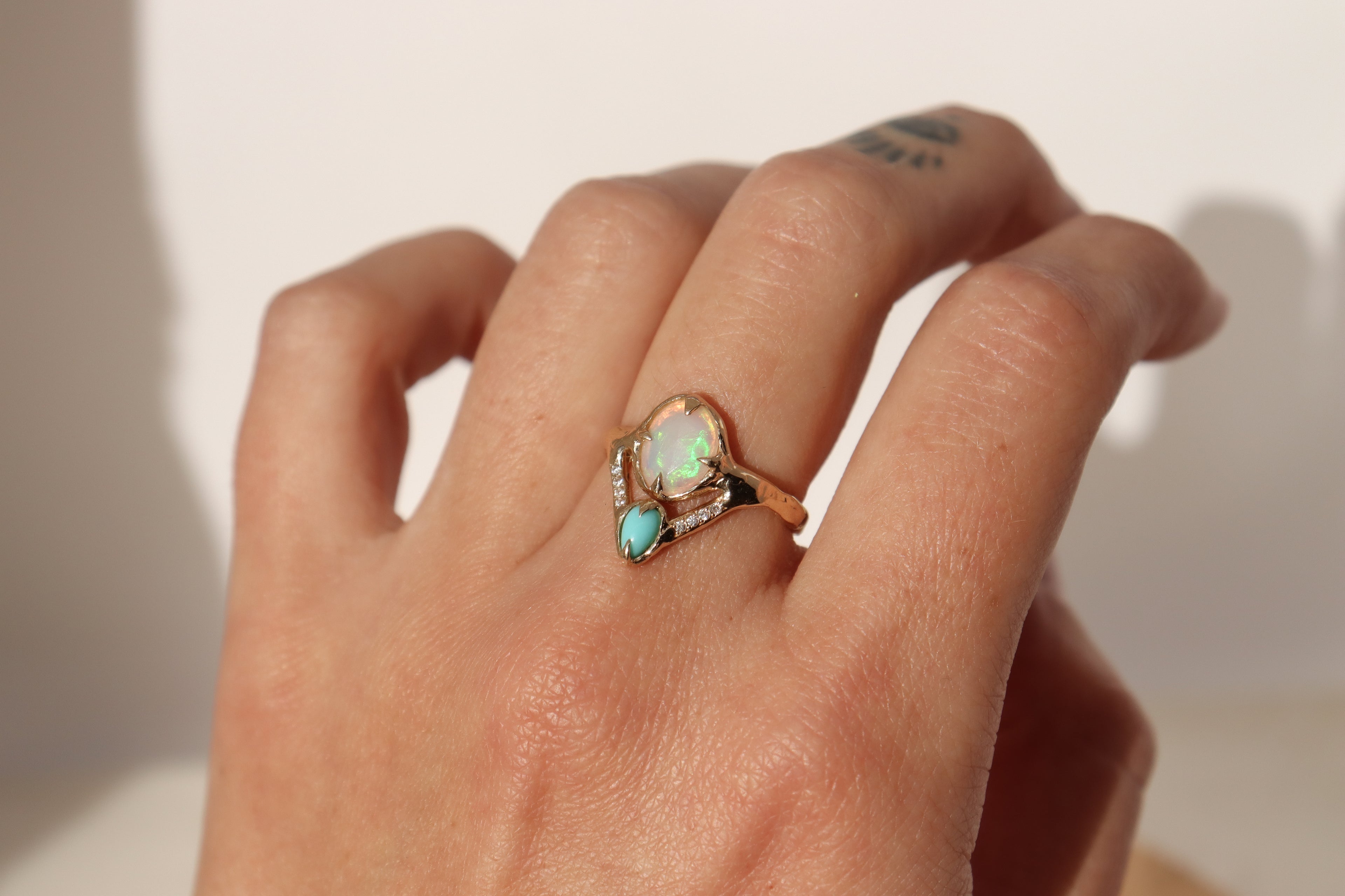 opal, turquoise, and diamond ring displayed on a models hand