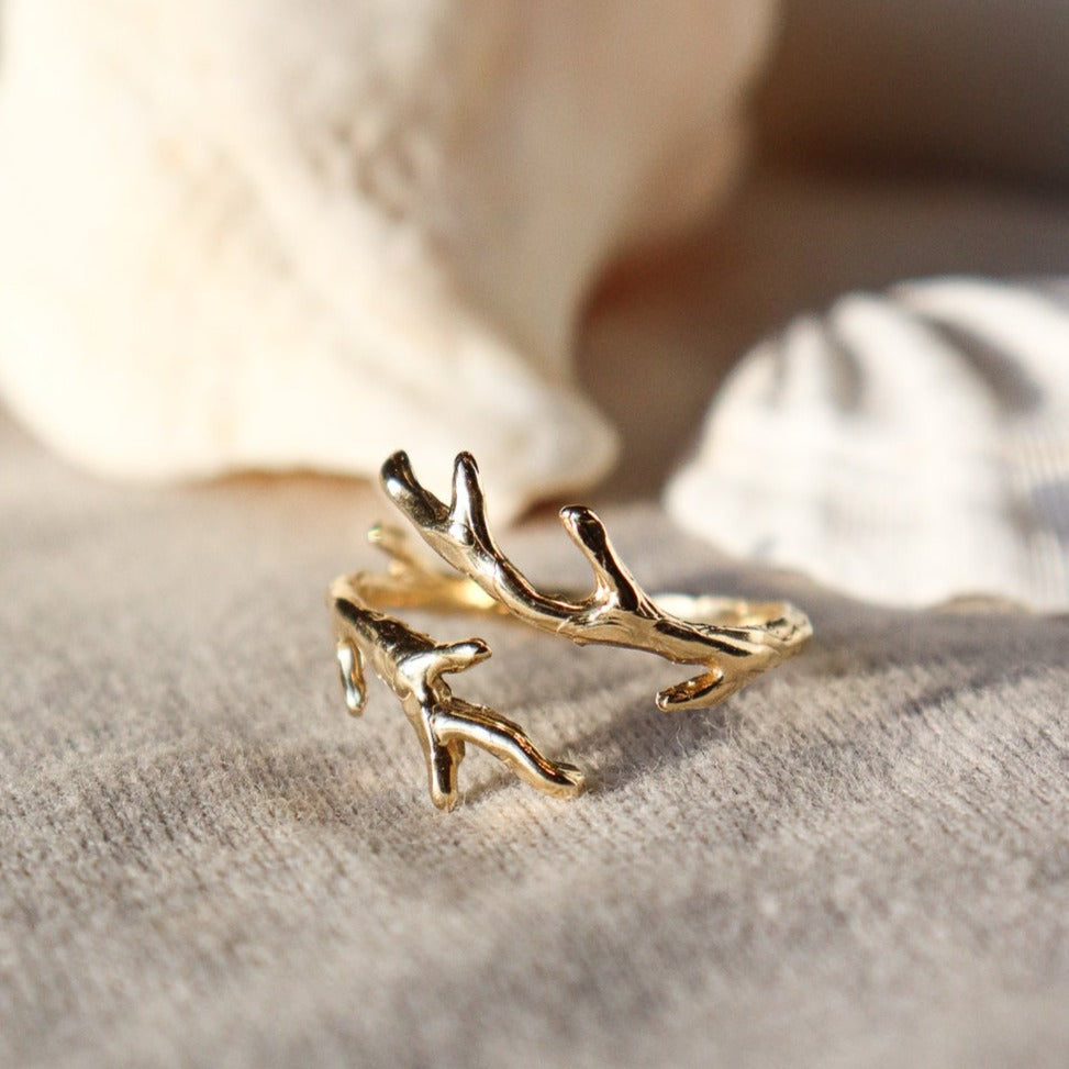 close up front view of a gold coral branch ring with seashells in the background