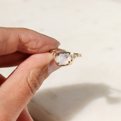 front view of a gold moonstone ring with diamonds on the sides of the band