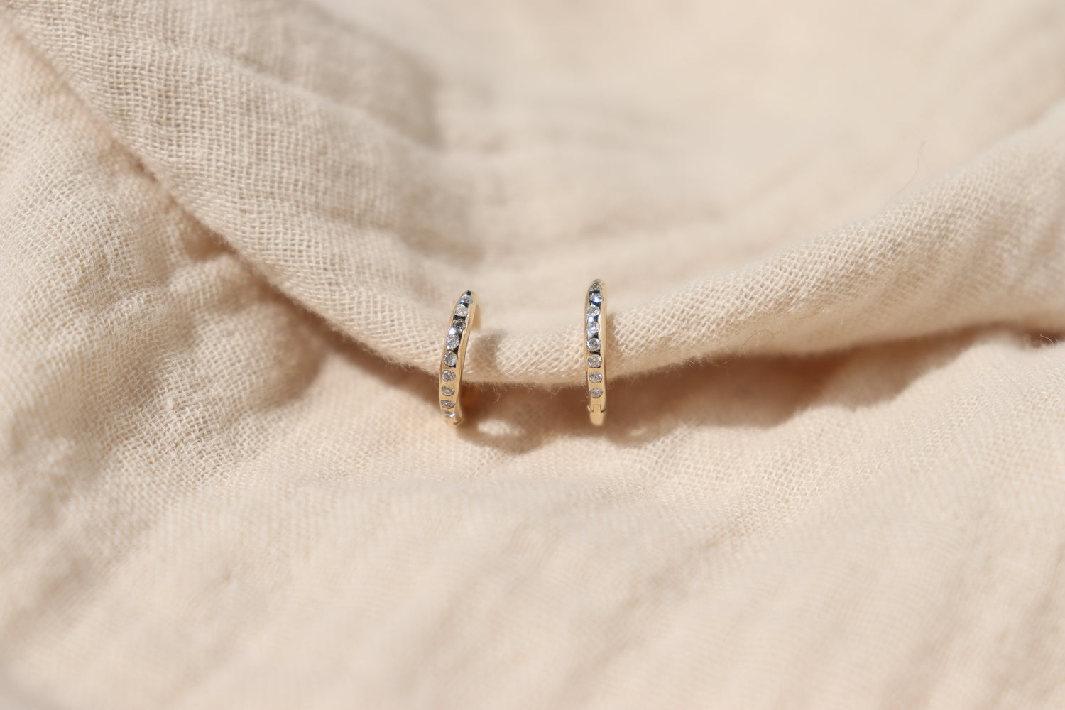 a front view of a pair of flush set diamond gold hoops