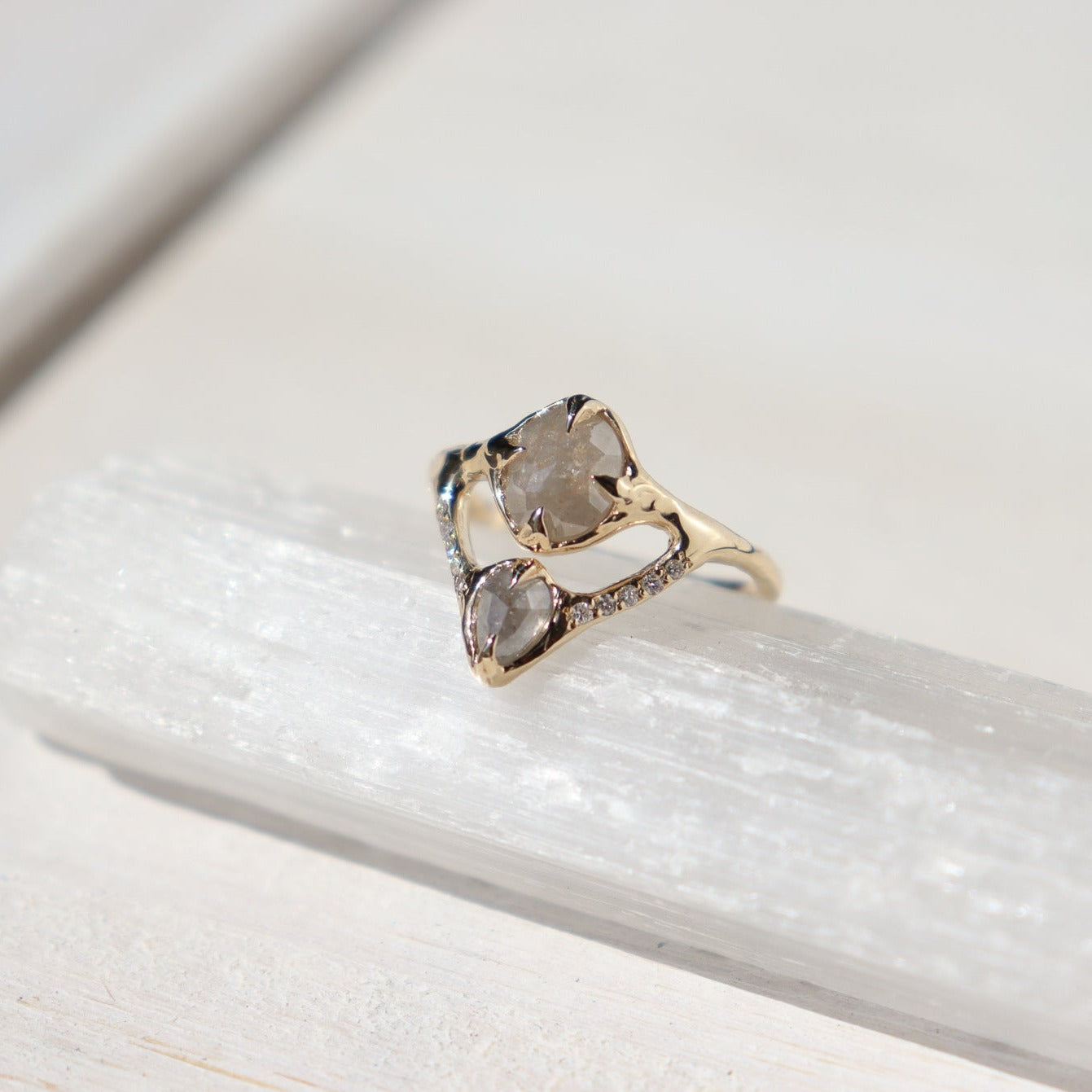 close up of a salt and pepper diamond ring on a crystal and white surface