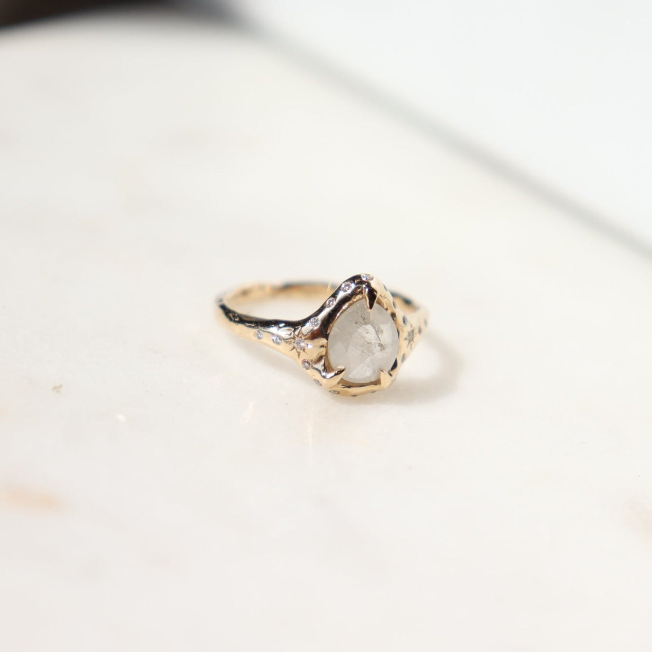 3/4 view of a white icy diamond ring that sits on a white surface