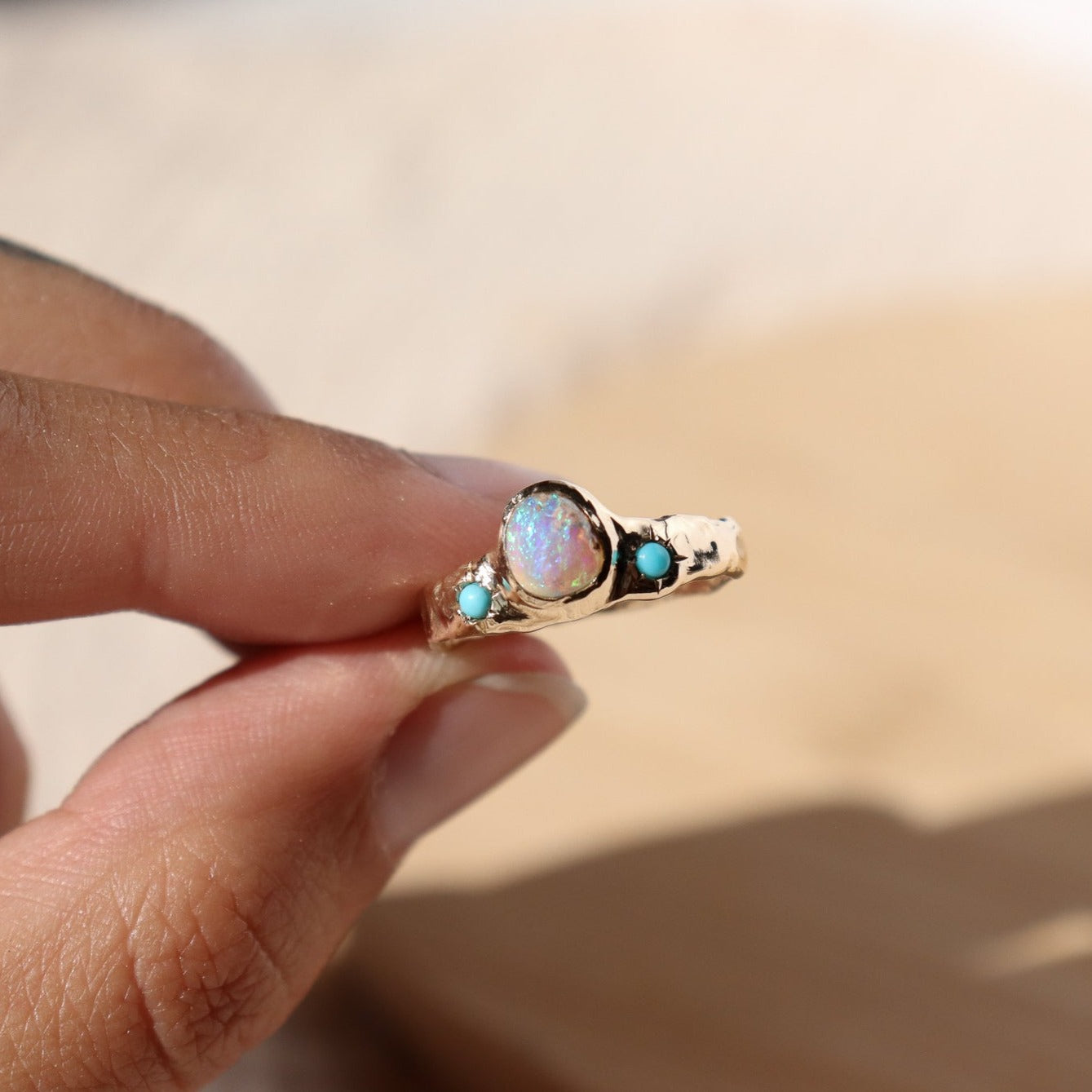 3/4 view of a wide gold band with a center opal and turquoise star settings