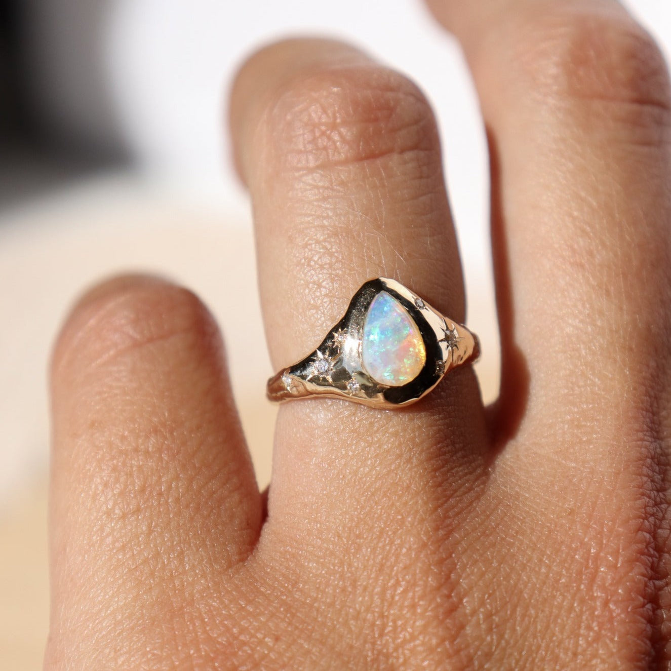 3/4 view of a gold opal ring with diamond star set accents