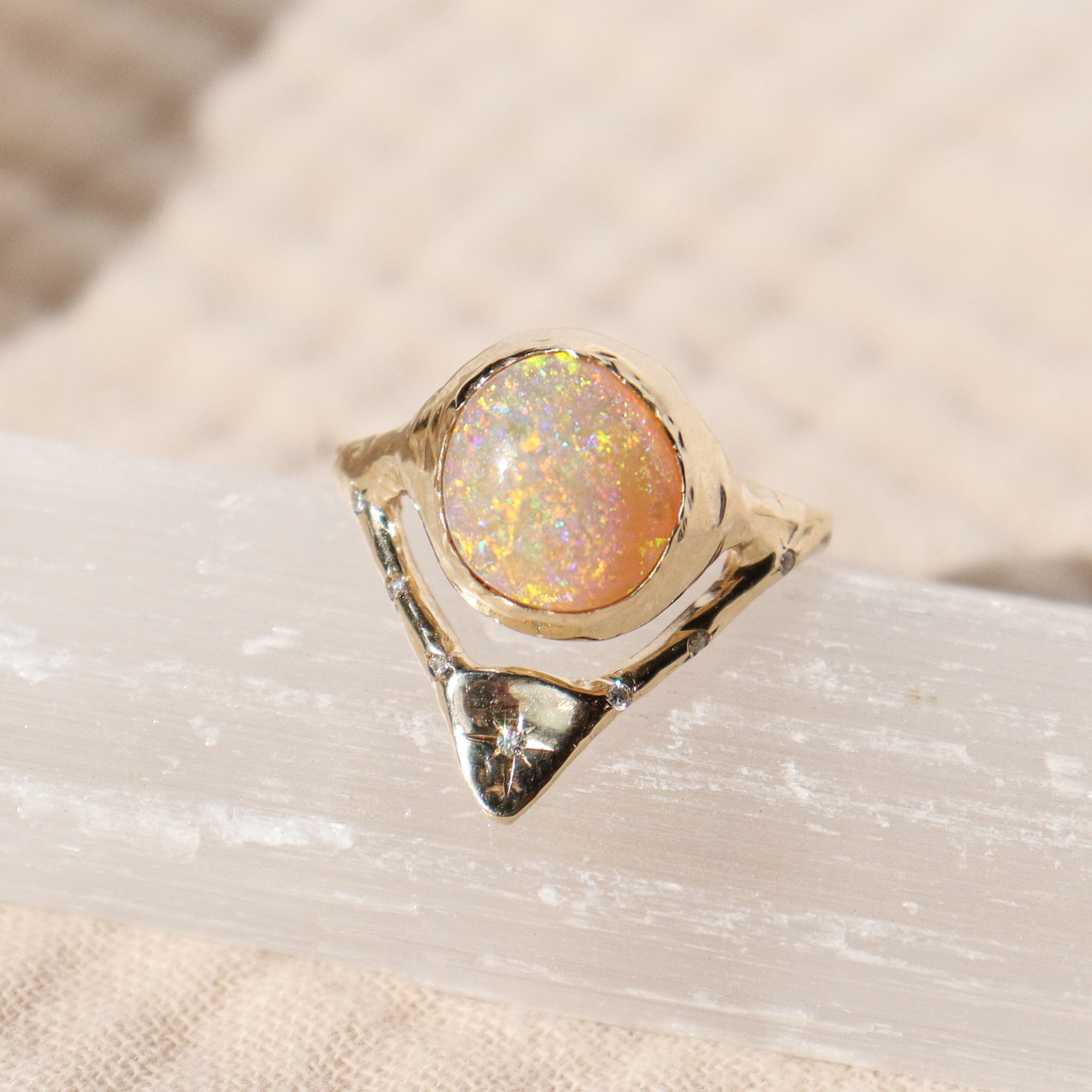 gold opal ring with diamonds on a light cream background