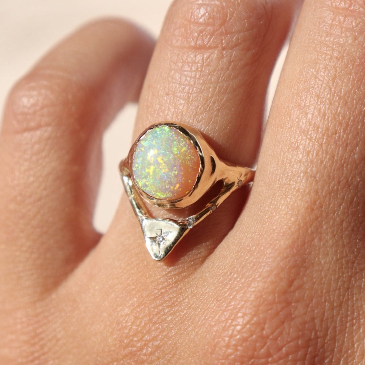 gold opal ring with diamonds is modeled on a ring finger
