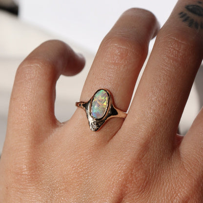 A long oval opal is bezel set in 14k gold  with  a star set  diamond at the base of the ring.