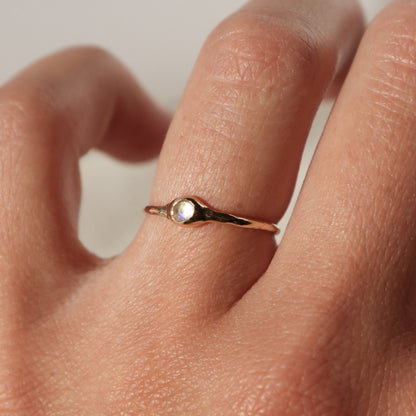 a tiny moonstone stacking ring worn on a ring finger