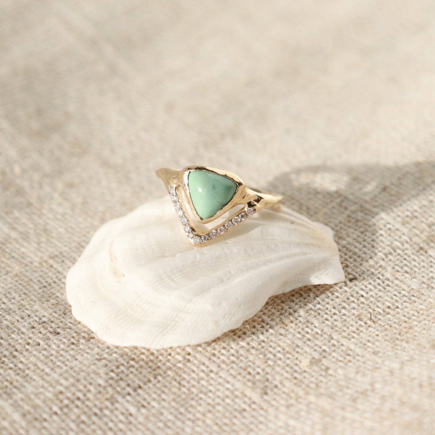 A trillion shaped variscite is bezel set with a V-shaped pave band at the base of the ring.