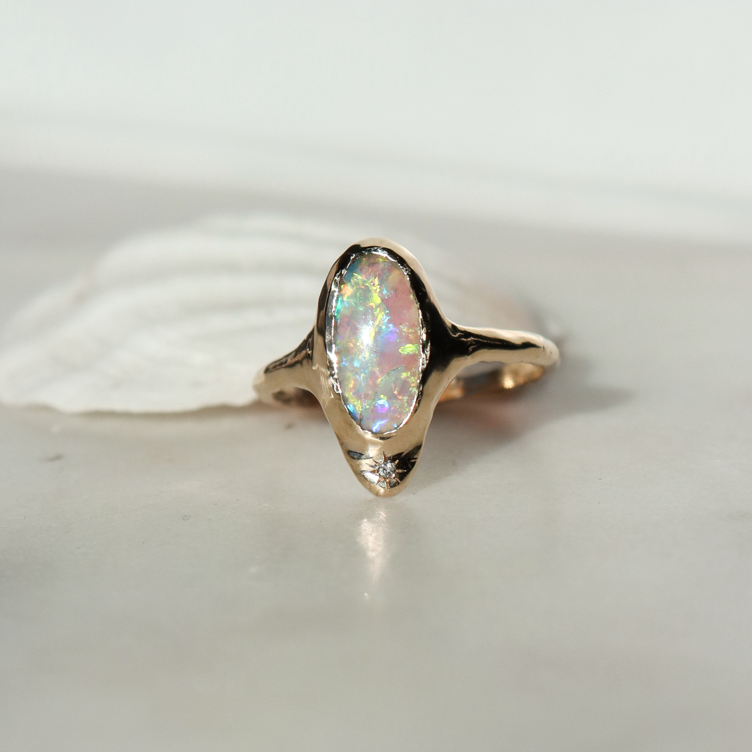 A long oval opal is bezel set in 14k gold  with  a star set  diamond at the base of the ring.