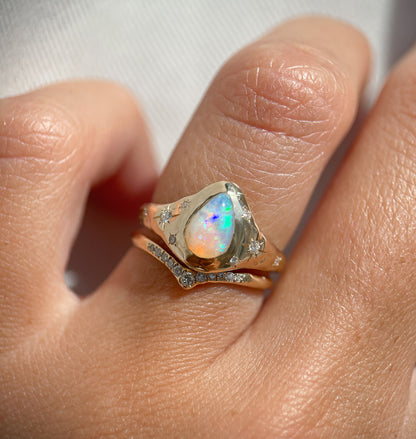 up close view of a gold opal ring that is signet style with star set diamond accents and paired with a pave diamond band