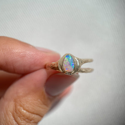 straight on view of a small pear shaped opal set in 14k gold with an asymmetric band design