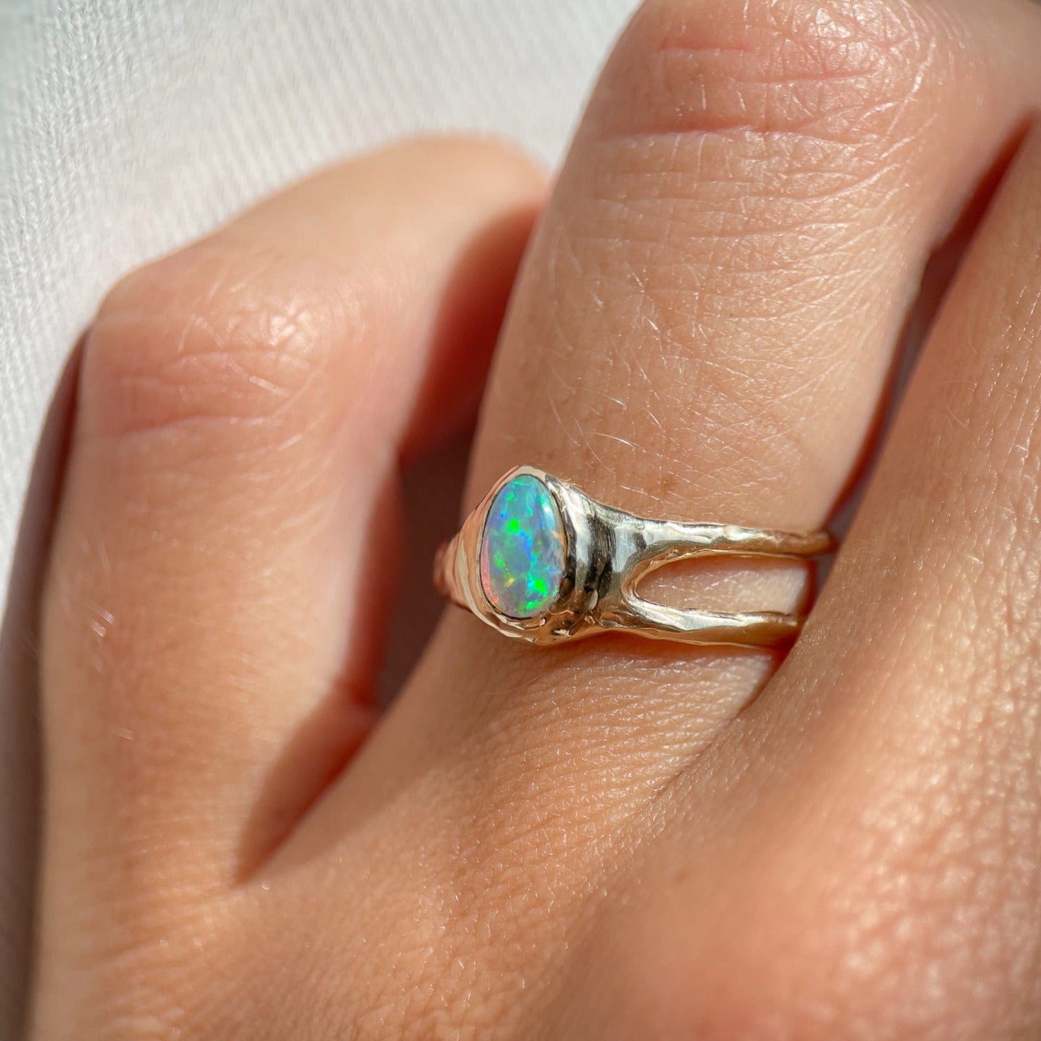 side view of a small pear shaped opal set in 14k gold with an asymmetric band design