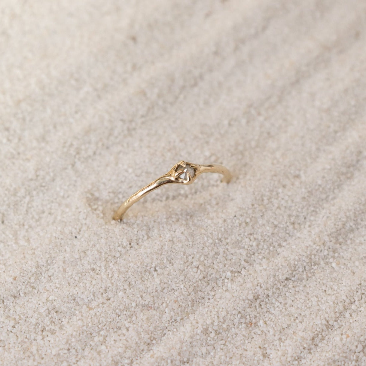 Tiny rose cut icy diamond is set with prongs on a narrow 14k gold band.