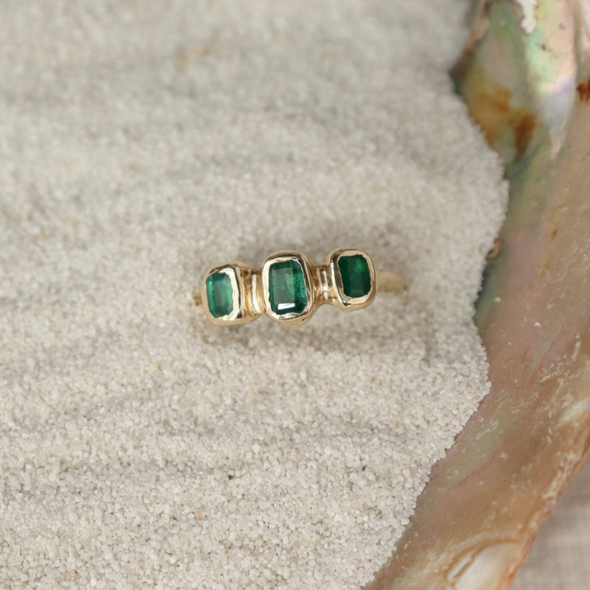 Three little emerald cut emeralds are embedded into a 14k gold ring giving it an organic look.