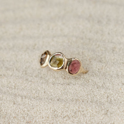 Watermelon tourmaline gemstones are bezel set along the front of a 14k gold band.