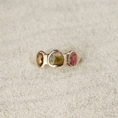 Watermelon tourmaline gemstones are bezel set along the front of a 14k gold band.