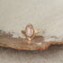 A rose cut pink tourmaline stone is bezel set on a V-shaped band.