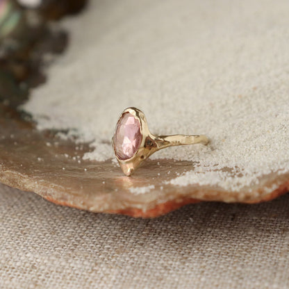 A rose cut pink tourmaline stone is bezel set on a V-shaped band.