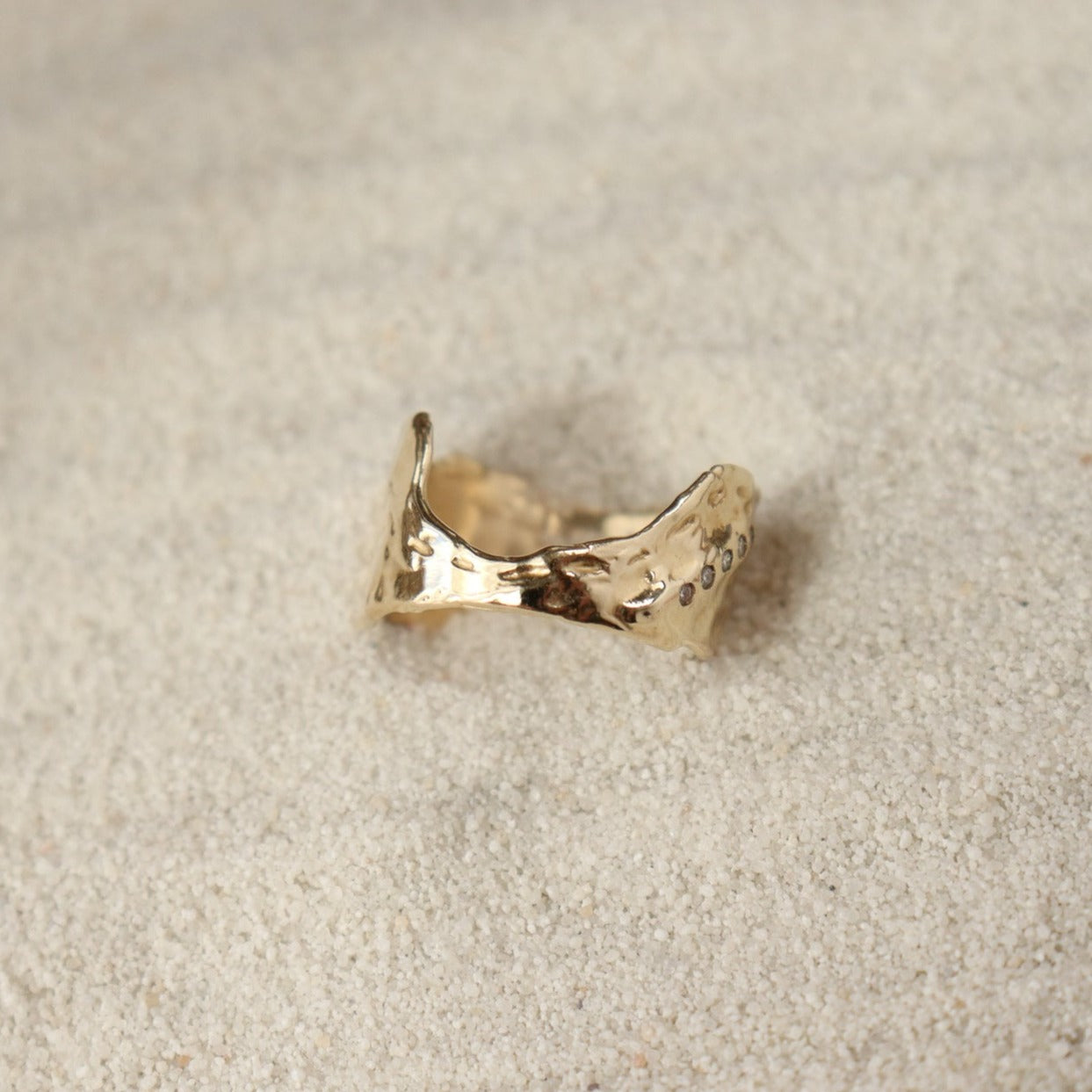 Front view of a wide textured band with a dip in the front to allow for stacking with a larger gemstone ring.
