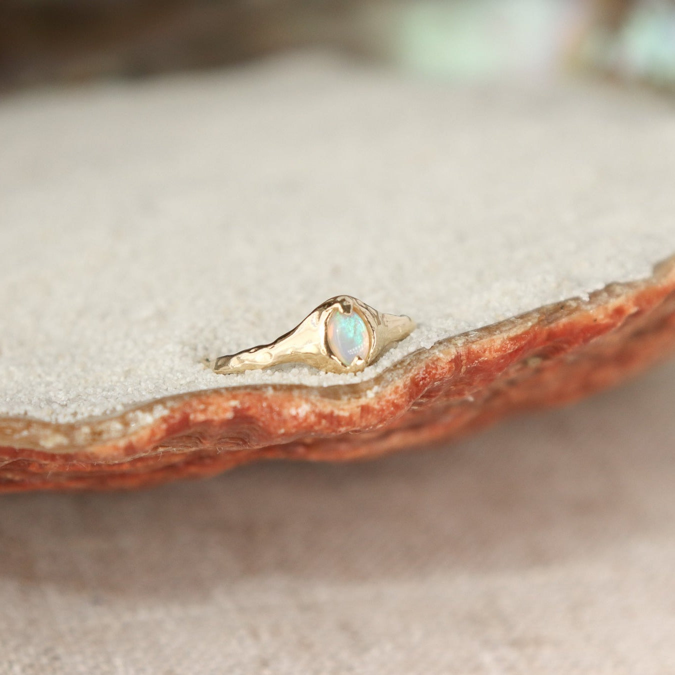 A small oval opal ring is set with prongs on an organically crafted 14k gold band.