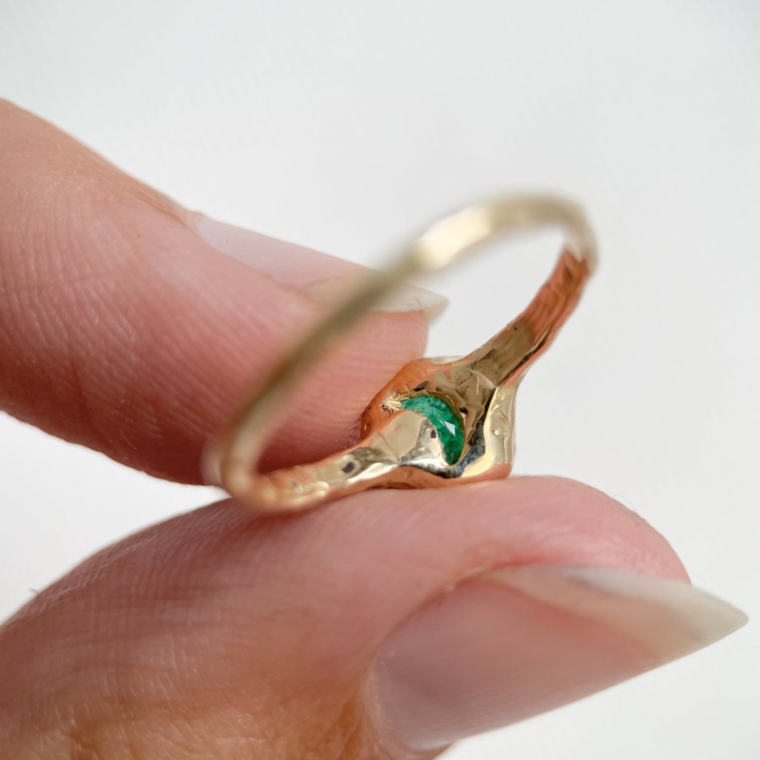 backside of a emerald ring with a moon carved out of the gold