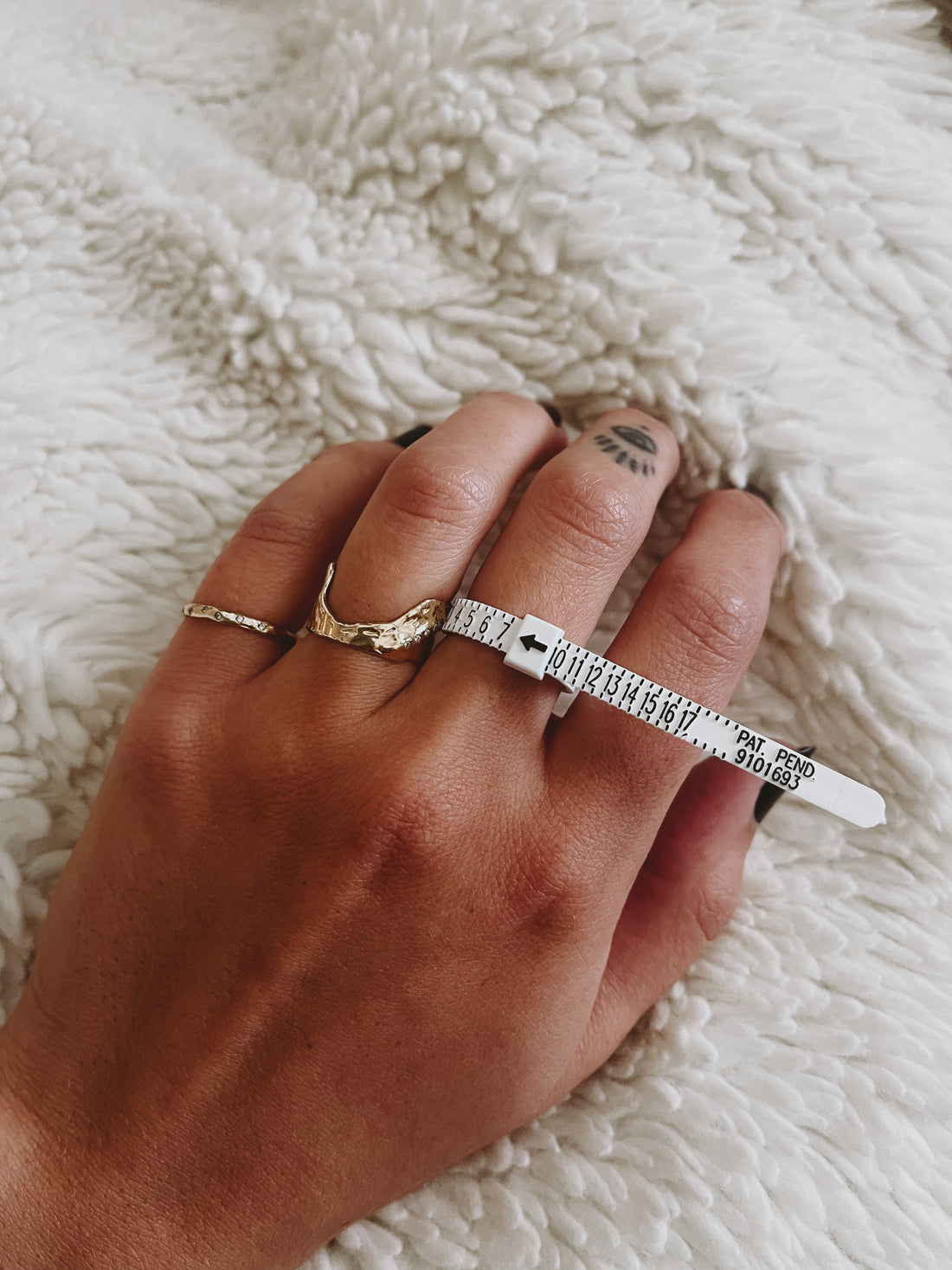 A ring sizing tool is shown on a models finger